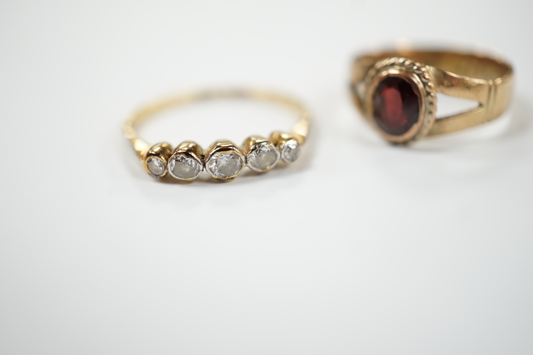 An 18ct, plat and graduated five stone diamond set half hoop ring, size M and a 14k and single stone garnet ring, size H.